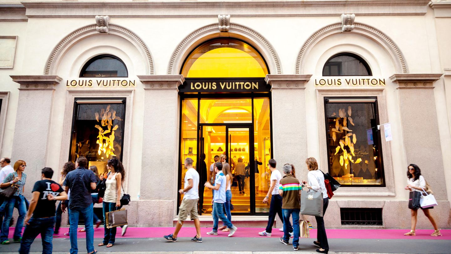 Menschen in einer luxuriösen Einkaufsstraße vor einer "Louis Vuitton"Filliale