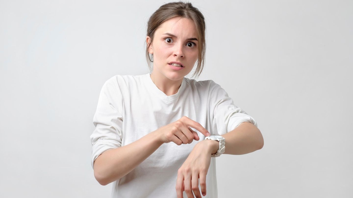 Frau zeigt hektisch auf ihre Uhr