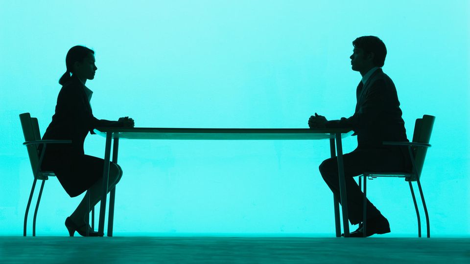 Frau und Mann setzen sich am Tisch gegenüber
