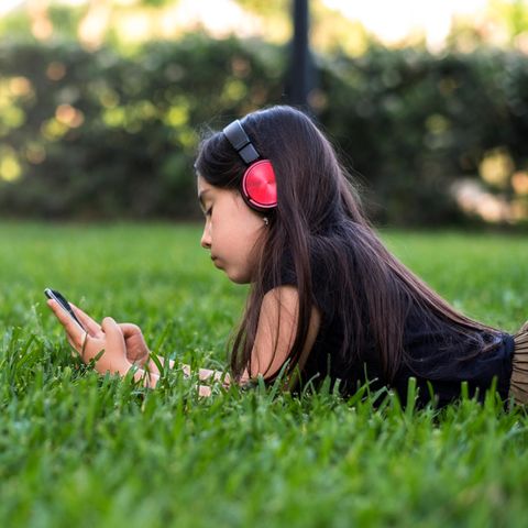 Mädchen spielt auf der Wiese am Handy