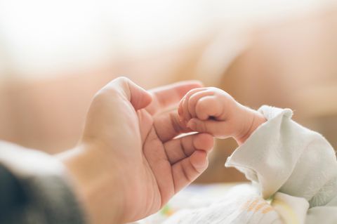 Neugeborenes hält den Finger der Mutter