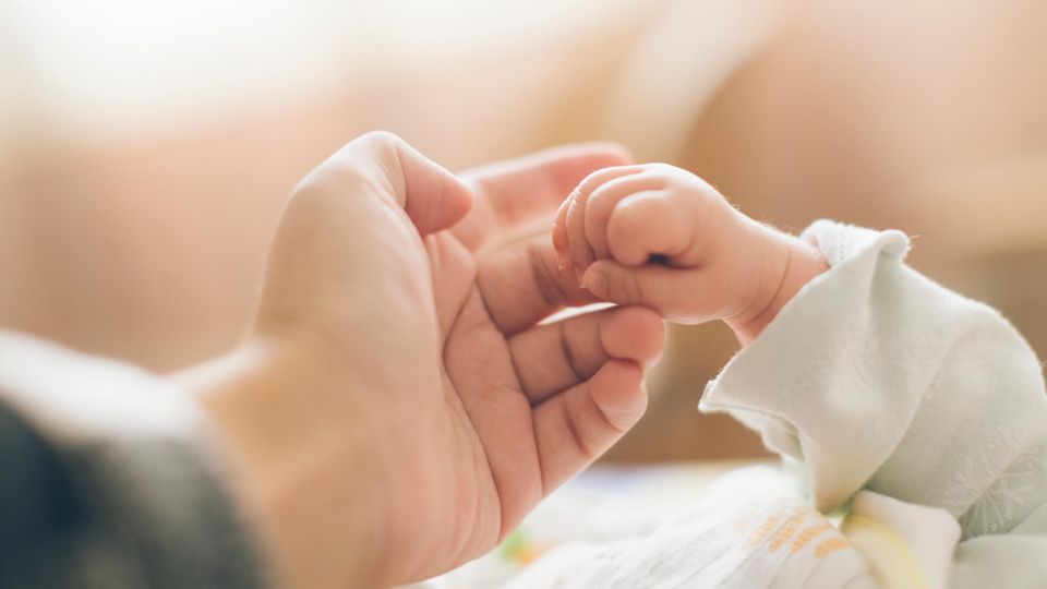 Neugeborenes hält den Finger der Mutter