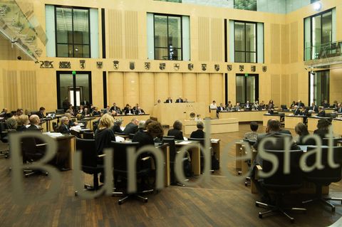 Durch eine Glasscheibe mit "Bundesrat"-Schriftzug ist ein voller Sitzungssaal mit Länderwappen zu sehen