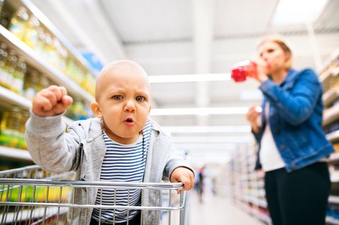Ein Baby im Einkaufswagen ballt eine Faust