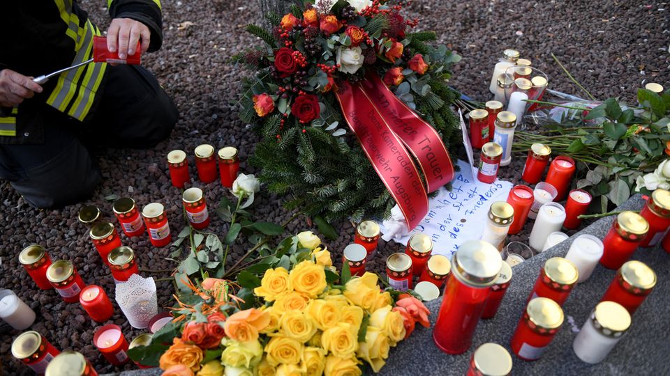 Ein Feuerwehrmann zündet am Königsplatz in Augsburg für seinen toten Kollegen eine Kerze an