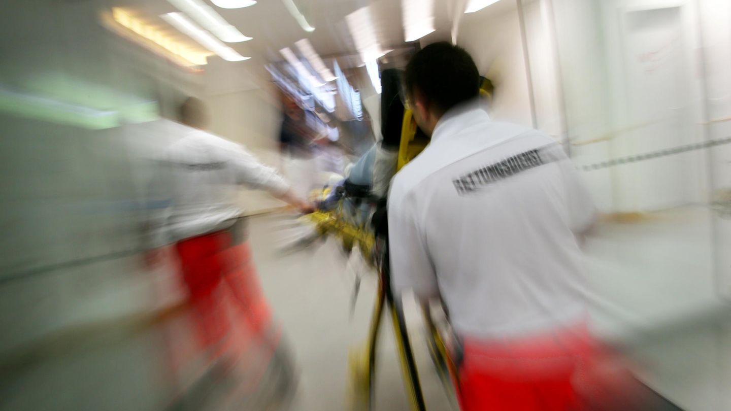 Rettungsassistenten des BRK liefern eine Notfallpatientin auf einer Trage in ein Krankenhaus ein