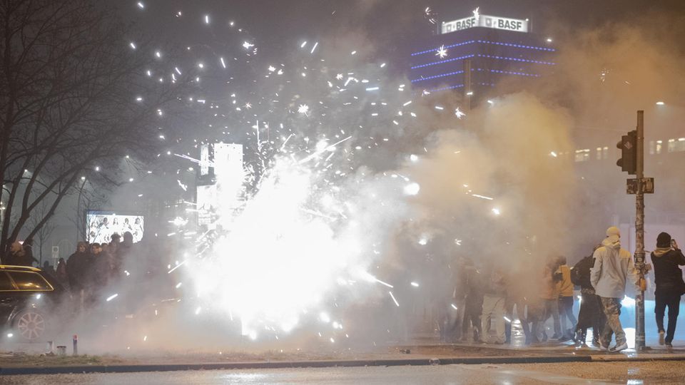 Böller und Raketen steigen in Berlin an der Oberbaumbrücke in die Luft, während Passanten vorbeigehen