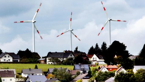 Windräder des Windparks Schöneseiffen drehen sich hinter Wohnhäusern