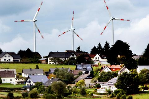 Windräder des Windparks Schöneseiffen drehen sich hinter Wohnhäusern