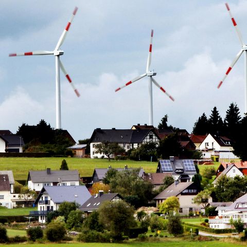 Windräder des Windparks Schöneseiffen drehen sich hinter Wohnhäusern
