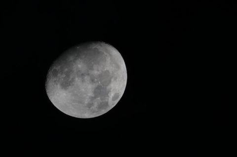 An einem schwarzen Himmel ist der Mond in Großaufnahme zu sehen. Er wirkt grau und seine Krater sind deutlich zu sehen