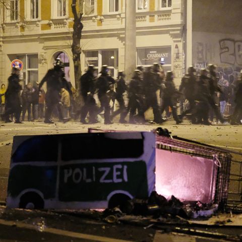 Polizeibeamte passieren in der Silvesternacht in Leipzig-Connewitz einen umgekippten Einkaufswagen