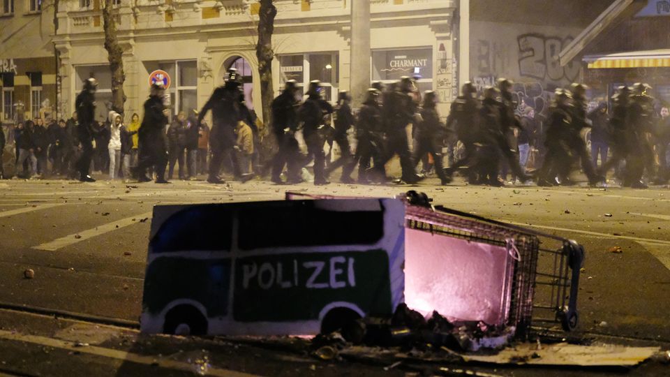 Polizeibeamte passieren in der Silvesternacht in Leipzig-Connewitz einen umgekippten Einkaufswagen