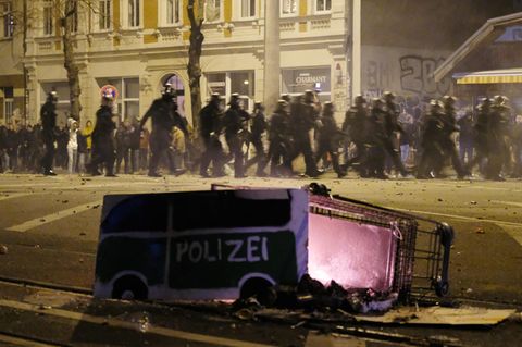 Polizeibeamte passieren in der Silvesternacht in Leipzig-Connewitz einen umgekippten Einkaufswagen