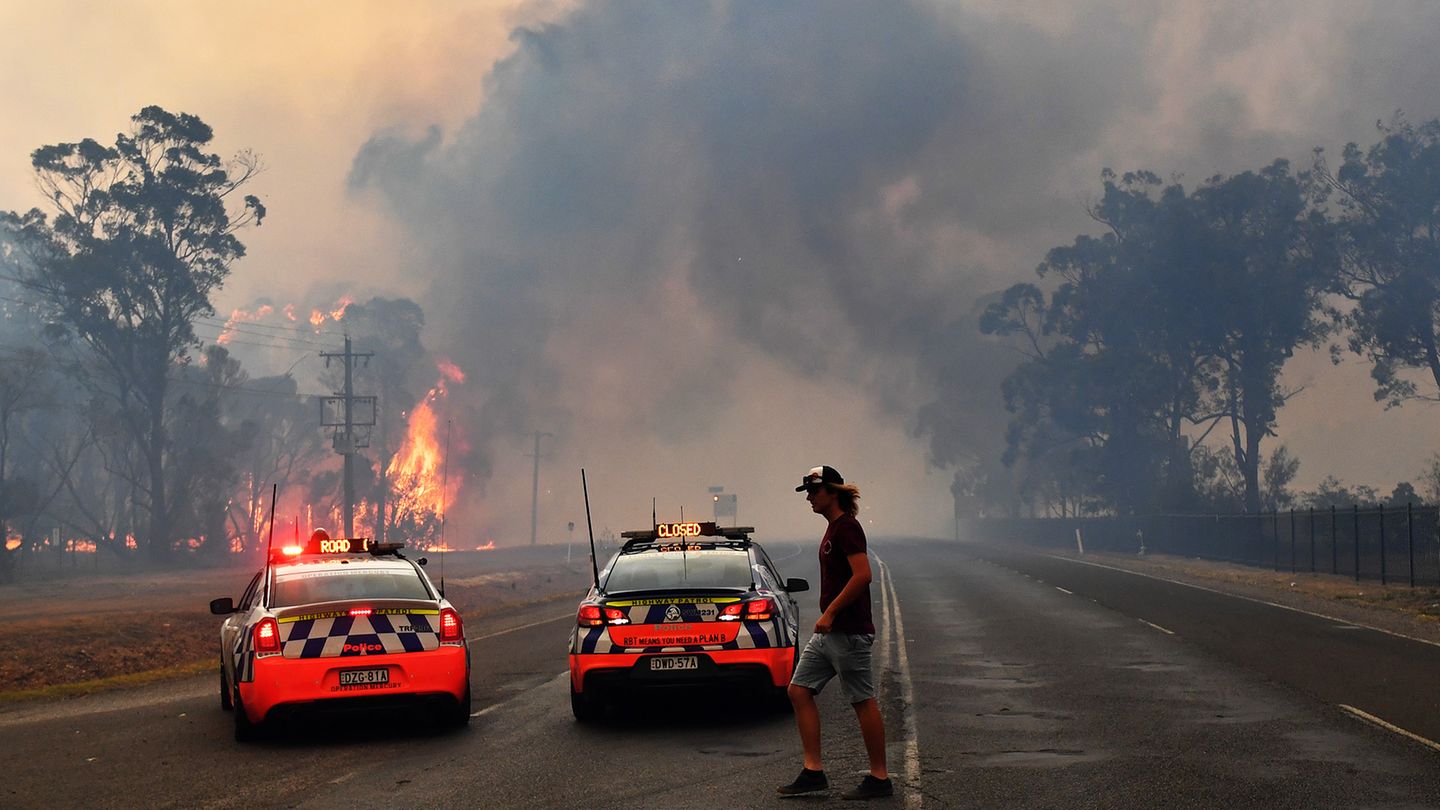 Die Polizei sperrt mit zwei Polizeiautos südwestlich von Sydney eine Straße zu einem Gebiet, das in Flammen steht. Aufgrund der verheerenden Buschbrände ist in Australiens bevölkerungsreichstem Bundesstaat New South Wales erneut der Notstand ausgerufen worden.