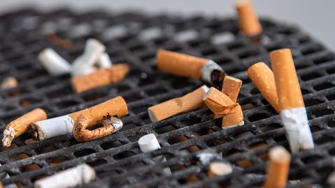 Zahlreiche Zigarettenstummel liegen in einem Aschenbecher vor einem Büro