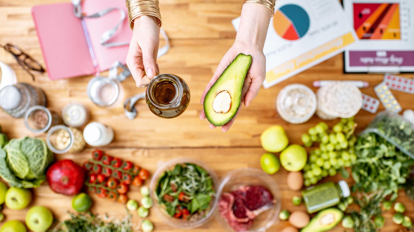 Frau hält Avocado und Öl