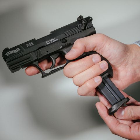 Hände laden eine Schreckschuss-Pistole «Walther P22» mit einem Magazin