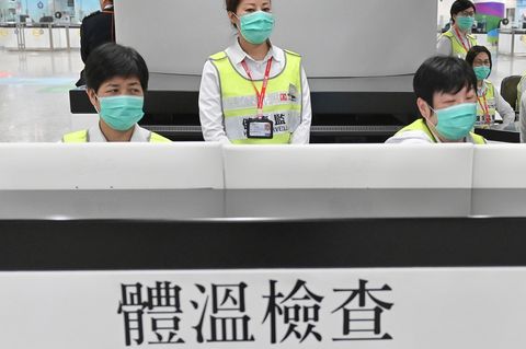 Mitarbeiter der Gesundheitsbehörden untersuchen Reisende am Hongkonger Bahnhof West Kowloon Station auf ihren Gesundheitszustand