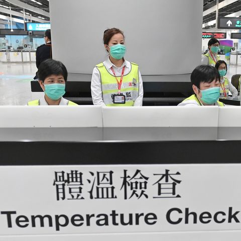 Mitarbeiter der Gesundheitsbehörden untersuchen Reisende am Hongkonger Bahnhof West Kowloon Station auf ihren Gesundheitszustand