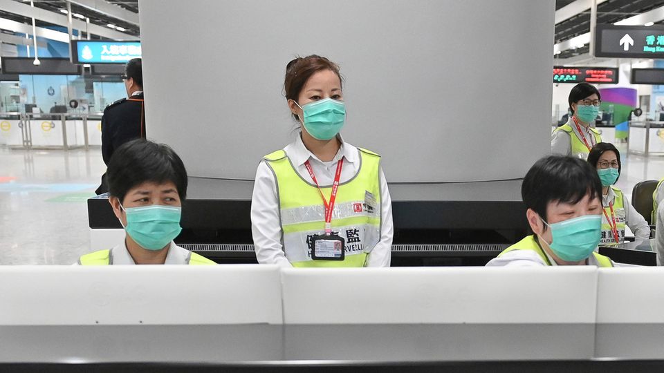 Mitarbeiter der Gesundheitsbehörden untersuchen Reisende am Hongkonger Bahnhof West Kowloon Station auf ihren Gesundheitszustand