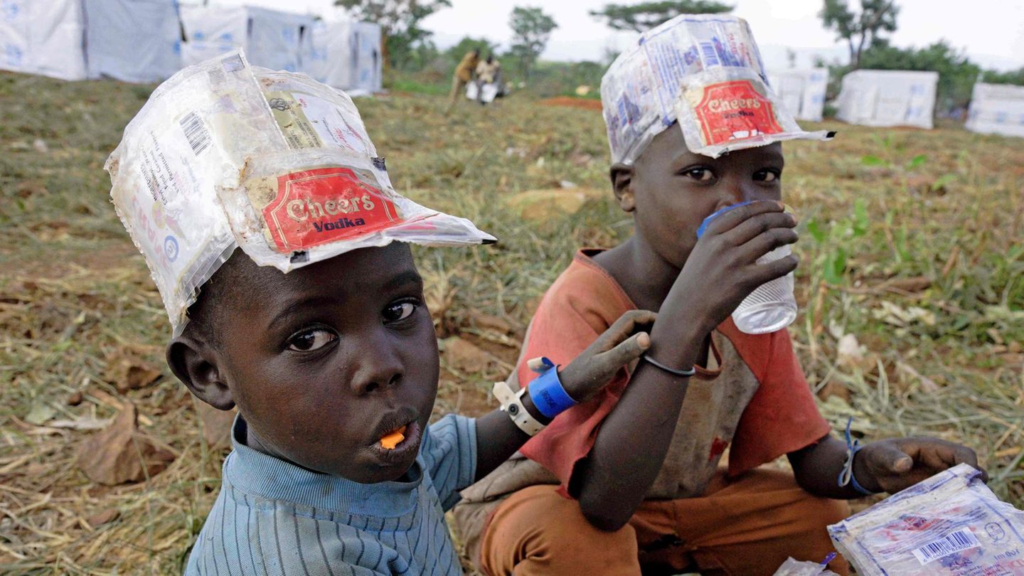 Zwei Flüchtlingsjungen in Uganda trinken und essen