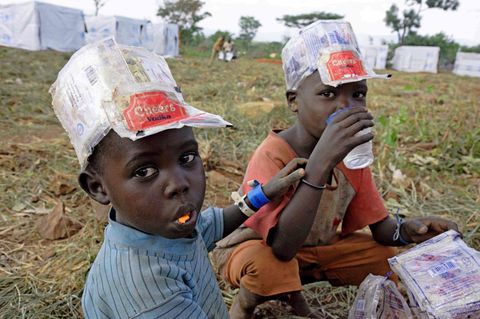 Zwei Flüchtlingsjungen in Uganda trinken und essen
