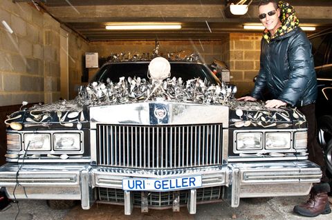 Uri Geller steht neben seinem Cadillac, auf dem Löffel befestigt sind