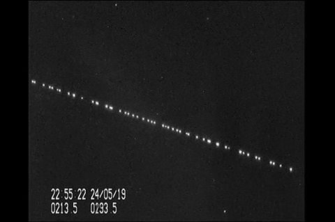 Helle Punkte ziehen in einer Reihe über den Sternenhimmel