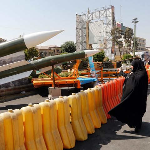 Eine Iranerin schaut sich mehrere ausgestellte Taer-2-Raketen an