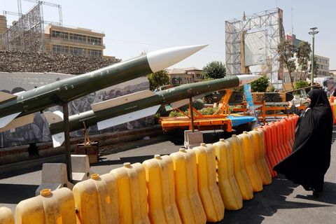 Eine Iranerin schaut sich mehrere ausgestellte Taer-2-Raketen an