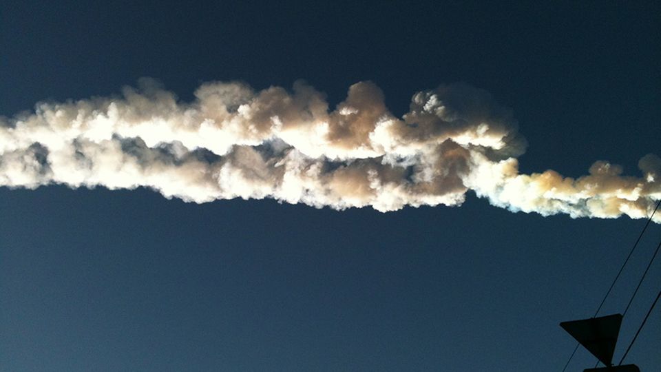 Ein Meteorit hinterlässt am Himmel über der Stadt eine weiße Spur Ein Meteorit hinterlässt am Himmel über der Stadt eine weiße Spur