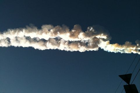 Ein Meteorit hinterlässt am Himmel über der Stadt eine weiße Spur