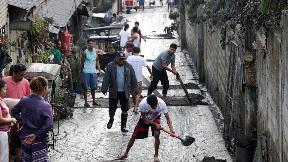 Philippinen, Cavite: Anwohner reinigen eine Straße von Asche