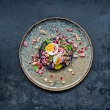 Rotkohlsteak mit Schinken-Granatapfel-Crumble      Für 4 Personen  1 mittelgroßer Rotkohl  Salz  Für den Schinken-Granatapfel-Crumble  2 rote Zwiebeln  2 EL Sonnenblumenöl  200 g geräucherte Schinkenwürfel  1 sehr kleine getrocknete Chilischote  4 EL Granatapfelkerne  Zum Anrichten  4 Eier (Größe M)  4 Stängel Dill  4 Stängel glatte Petersilie  60 g Walnusskerne  Zubereitungszeit 25 Min + 1 h Garzeit      Zubereitung  • Den Backofen auf 250°C (Umluft) vorheizen. Den Rotkohl waschen, trocken tupfen und auf den Rost in den Ofen legen. Ein Backblech darunter schieben, da der Kohl beim Garen tropft. Kohl im Ofen 1–1 ½ Stunden verbrennen lassen. Eine Garprobe (zum Beispiel mit einer Messerspitze) machen, der Kohl sollte weder weich noch zu fest sein.  • Inzwischen für den Schinken-Crumble die Zwiebeln abziehen und fein würfeln. Das Öl in einer Pfanne erhitzen und die Zwiebelwürfel darin bei mittlerer Hitze etwa 4 Minuten anschwitzen, dabei öfter umrühren. Die Schinkenwürfel dazugeben und alles weitere 2–3 Minuten braten. Die Chilischote zerbröseln, untermengen und die Pfanne vom Herd nehmen. Die Granatapfelkerne unter den leicht abgekühlten Zwiebel-Schinken-Mix heben.  • Die Eier in kochendem Wasser in 6 Minuten wachsweich kochen. Abschrecken und pellen.  • Dill und Petersilie waschen, trocken schütteln und die Spitzen beziehungsweise Blätter abzupfen. Die Walnusskerne grob hacken und in einer Pfanne ohne Fett bei mittlerer Hitze unter Rühren rösten, bis sie duften. Auf einem Teller abkühlen lassen.  • Den Rotkohl aus dem Ofen nehmen, die äußeren, dunklen Blätter entfernen und den Kohl in 1,5 – 2 cm dicke Scheiben ("Steaks") schneiden. Je ein Steak pro Teller anrichten, leicht mit Salz würzen und 2–3 EL Crumble daraufgeben. Eier halbieren, mit etwas Salz bestreuen und jeweils zwei Hälften auf den Teller legen. Mit Kräutern und Walnusskernen bestreut servieren.      Nährwerte pro Portion: Kcal 467 | E 26 g | F 31 g | KH 14 g