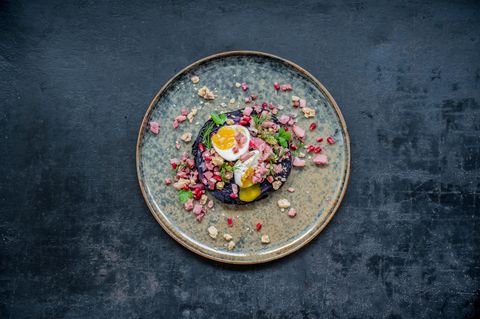 Rotkohlsteak mit Schinken-Granatapfel-Crumble      Für 4 Personen  1 mittelgroßer Rotkohl  Salz  Für den Schinken-Granatapfel-Crumble  2 rote Zwiebeln  2 EL Sonnenblumenöl  200 g geräucherte Schinkenwürfel  1 sehr kleine getrocknete Chilischote  4 EL Granatapfelkerne  Zum Anrichten  4 Eier (Größe M)  4 Stängel Dill  4 Stängel glatte Petersilie  60 g Walnusskerne  Zubereitungszeit 25 Min + 1 h Garzeit      Zubereitung  • Den Backofen auf 250°C (Umluft) vorheizen. Den Rotkohl waschen, trocken tupfen und auf den Rost in den Ofen legen. Ein Backblech darunter schieben, da der Kohl beim Garen tropft. Kohl im Ofen 1–1 ½ Stunden verbrennen lassen. Eine Garprobe (zum Beispiel mit einer Messerspitze) machen, der Kohl sollte weder weich noch zu fest sein.  • Inzwischen für den Schinken-Crumble die Zwiebeln abziehen und fein würfeln. Das Öl in einer Pfanne erhitzen und die Zwiebelwürfel darin bei mittlerer Hitze etwa 4 Minuten anschwitzen, dabei öfter umrühren. Die Schinkenwürfel dazugeben und alles weitere 2–3 Minuten braten. Die Chilischote zerbröseln, untermengen und die Pfanne vom Herd nehmen. Die Granatapfelkerne unter den leicht abgekühlten Zwiebel-Schinken-Mix heben.  • Die Eier in kochendem Wasser in 6 Minuten wachsweich kochen. Abschrecken und pellen.  • Dill und Petersilie waschen, trocken schütteln und die Spitzen beziehungsweise Blätter abzupfen. Die Walnusskerne grob hacken und in einer Pfanne ohne Fett bei mittlerer Hitze unter Rühren rösten, bis sie duften. Auf einem Teller abkühlen lassen.  • Den Rotkohl aus dem Ofen nehmen, die äußeren, dunklen Blätter entfernen und den Kohl in 1,5 – 2 cm dicke Scheiben ("Steaks") schneiden. Je ein Steak pro Teller anrichten, leicht mit Salz würzen und 2–3 EL Crumble daraufgeben. Eier halbieren, mit etwas Salz bestreuen und jeweils zwei Hälften auf den Teller legen. Mit Kräutern und Walnusskernen bestreut servieren.      Nährwerte pro Portion: Kcal 467 | E 26 g | F 31 g | KH 14 g