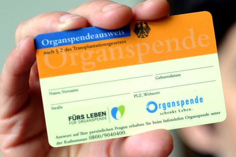 Eine Frau hält einen Organspendeausweis in der Hand