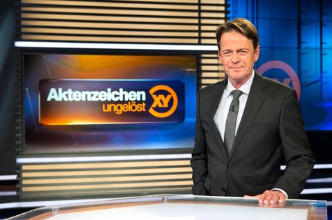 Moderator Rudi Cerne mit dem Logo der Sendung Aktenzeichen XY"