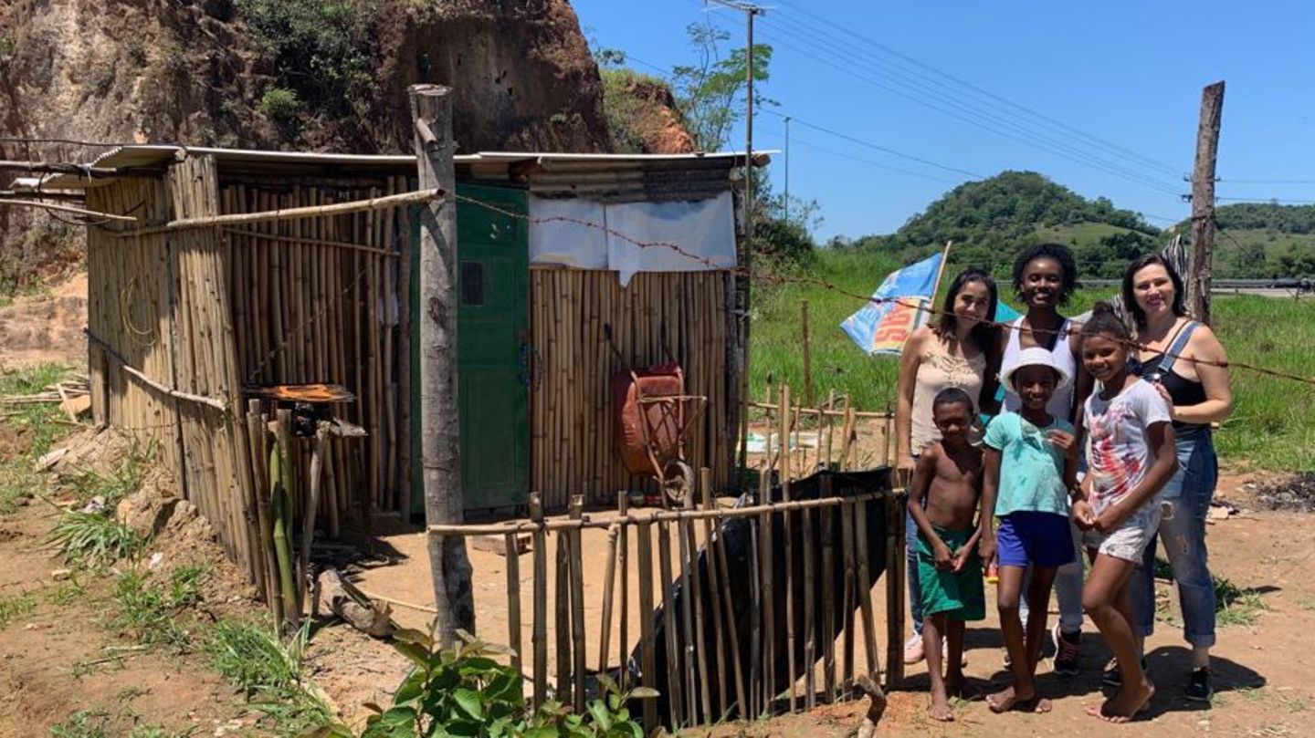 Kinder in der Armengegend von Jororó zeigen den helfenden Frauen (hintere Reihe) ihre Hütte