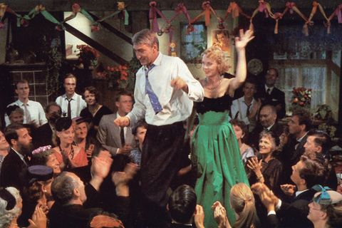 Pärchen tanzt auf einem Tisch, umgeben von Menschen