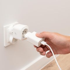 Man steckt das Ladegerät in die intelligente Steckdose