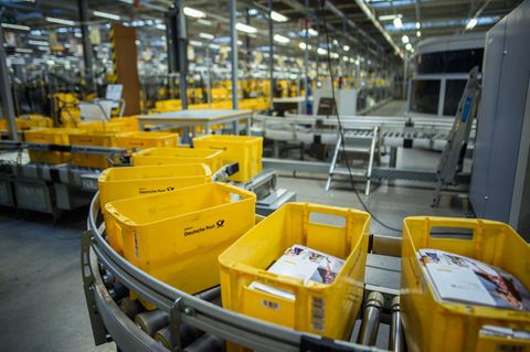 Gelbe Kisten zum Sortieren von Briefen laufen im Briefzentrum Kiel der Deutschen Post über ein Förderband