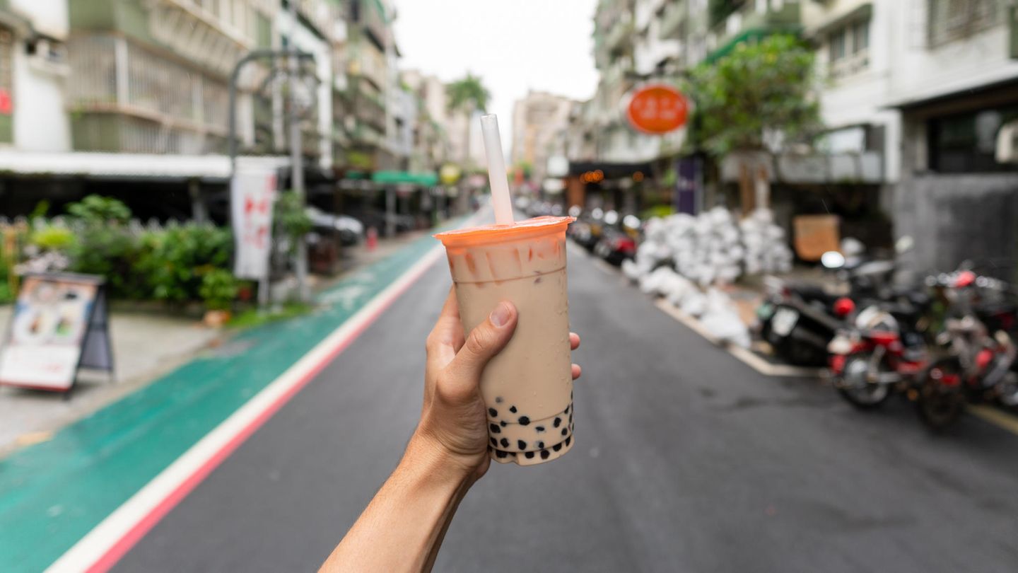 Eine Hand hält einen Plastikbecher mit Bubble Tea