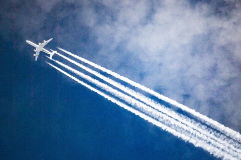 Ein Flugzeug zieht Kondensstreifen hinter sich her, während es durch die Wolken fliegt
