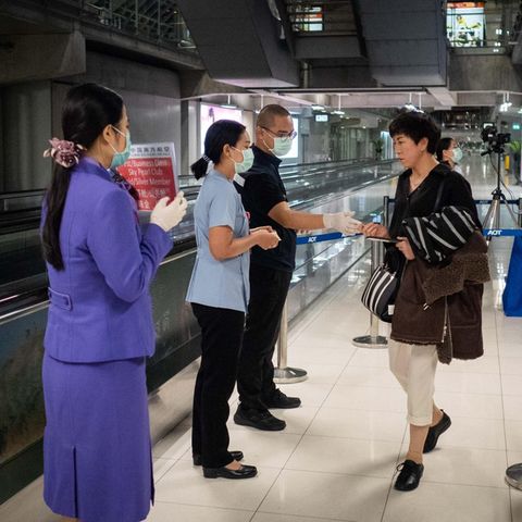 Passagiere erhalten Flugblätter zum Coronavirus am Flughafen in Bangkok