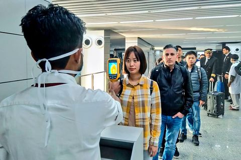 Coronavirus: Ein Flughafenmitarbeiter untersucht Reisende, die aus China und Hongkong ankommen