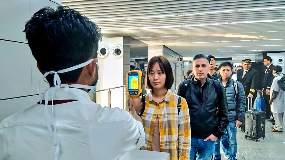 Coronavirus: Ein Flughafenmitarbeiter untersucht Reisende, die aus China und Hongkong ankommen