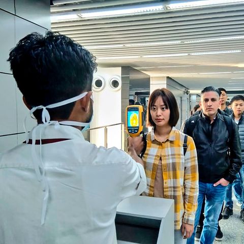 Coronavirus: Ein Flughafenmitarbeiter untersucht Reisende, die aus China und Hongkong ankommen
