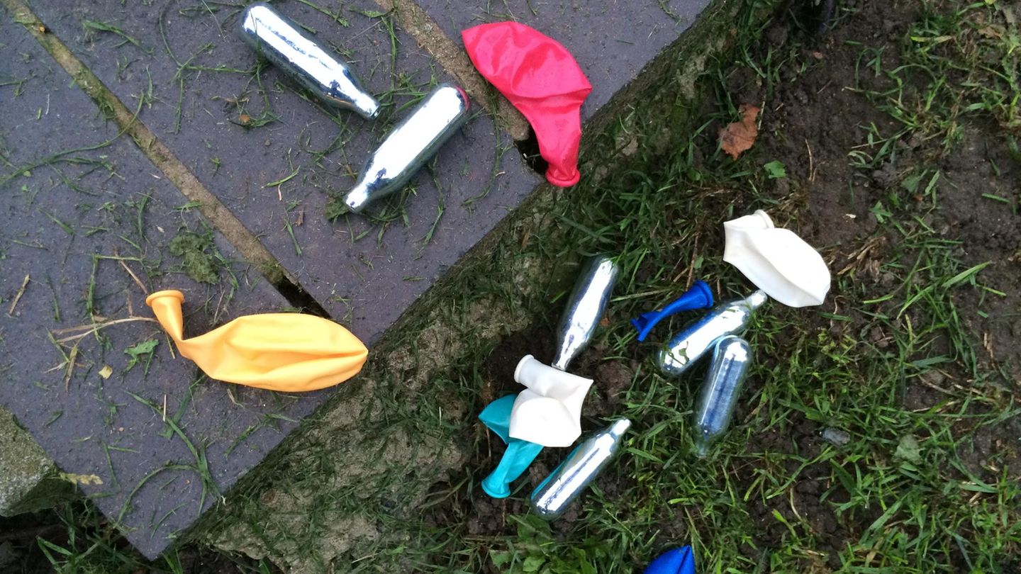 Lachgas-Kartuschen und Luftballons liegen auf dem Boden