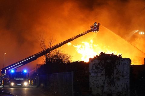 Ilsfeld: Feuerwehrleute versuchen Stapel von brennenden Holzpaletten zu löschen